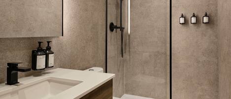 Un baño moderno con cabina de ducha de vidrio, un lavabo blanco y dos dispensadores de jabón.