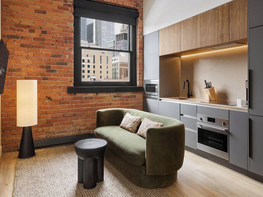 Una cocina moderna con pared de ladrillo, un sofá, una lámpara y una ventana con vista a la ciudad.