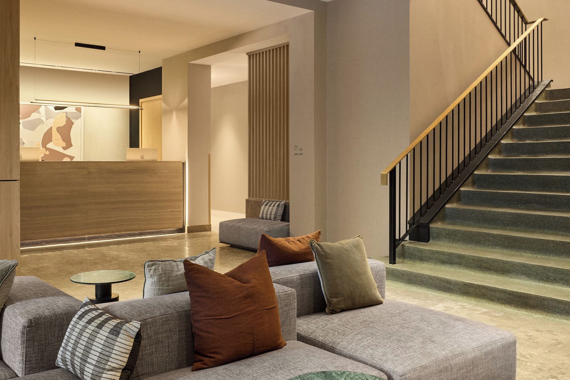 Un interior moderno con una escalera, un mostrador de recepción y una zona de estar.