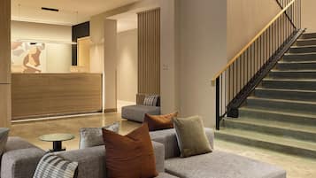 Un interior moderno con una escalera, un mostrador de recepción y una zona de estar.