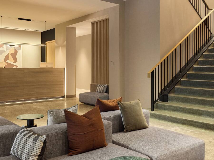 A modern interior with a staircase, a reception desk, and a seating area.
