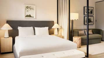 Una habitación de hotel con una cama grande, dos lámparas de noche, un sofá, una mesita y un cuadro en la pared.