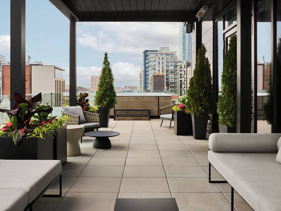 A rooftop terrace with outdoor seating, potted plants, and a view of the cityscape.