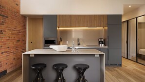 Una cocina moderna con una isla central, taburetes de bar, microondas y cafetera.