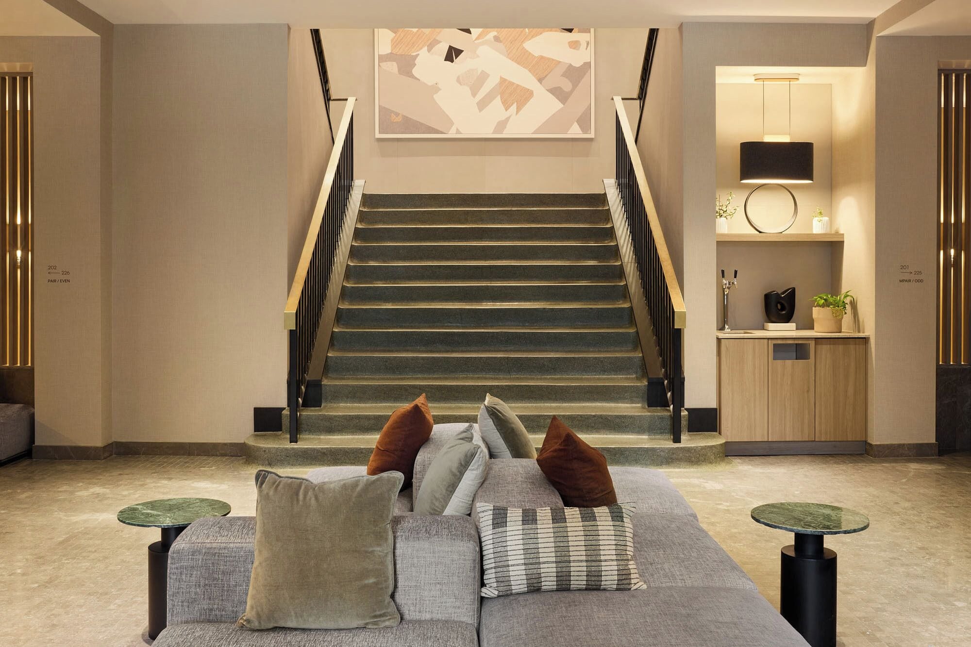 A modern interior with a staircase, a sofa with cushions, and a small table.