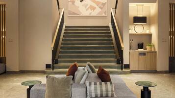A modern interior with a staircase, a sofa with cushions, and a small table.