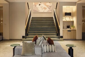 Un intérieur moderne avec un escalier, un canapé agrémenté de coussins et une petite table.
