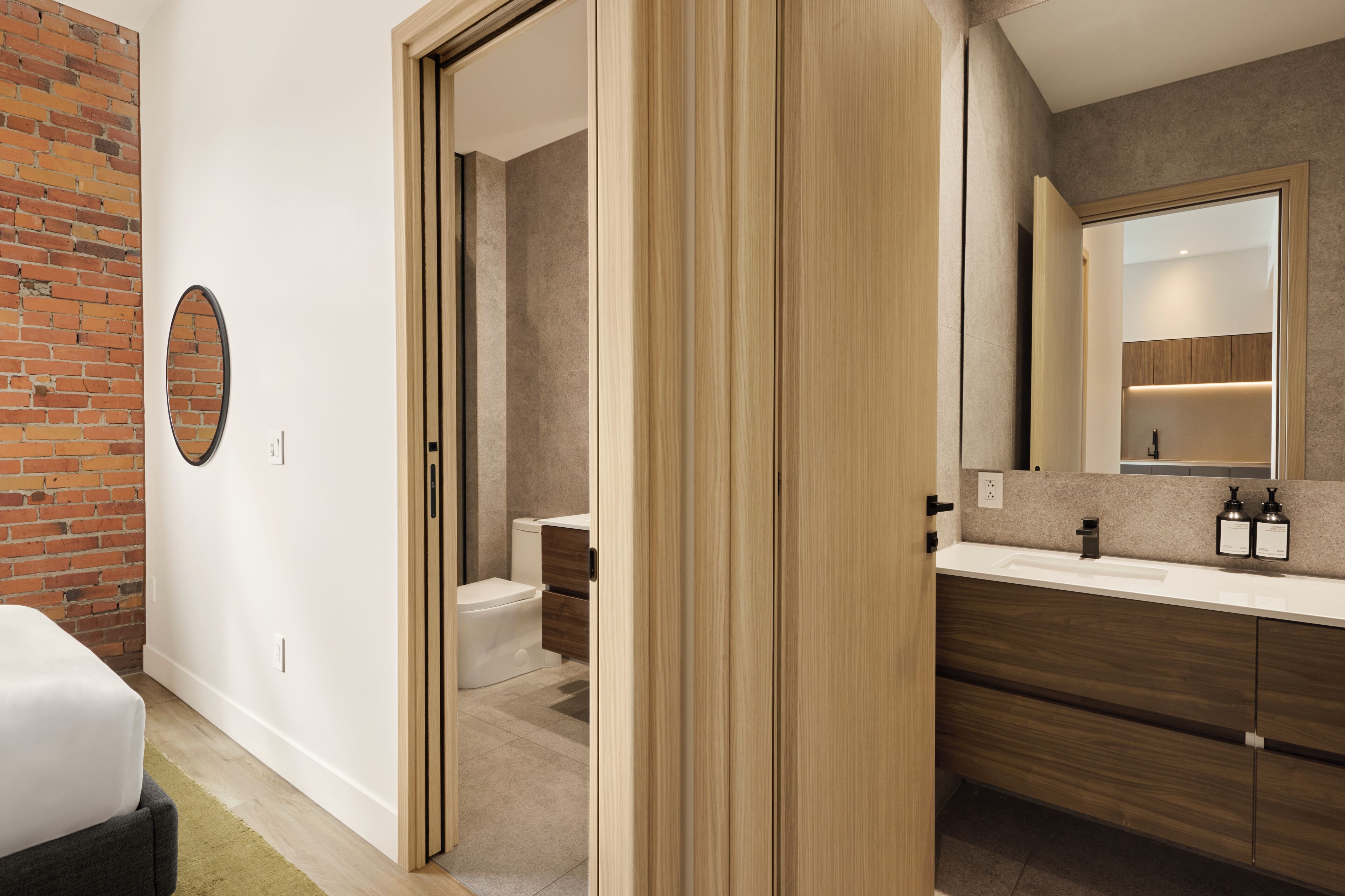 Un baño moderno con tocador de madera, inodoro y espejo.