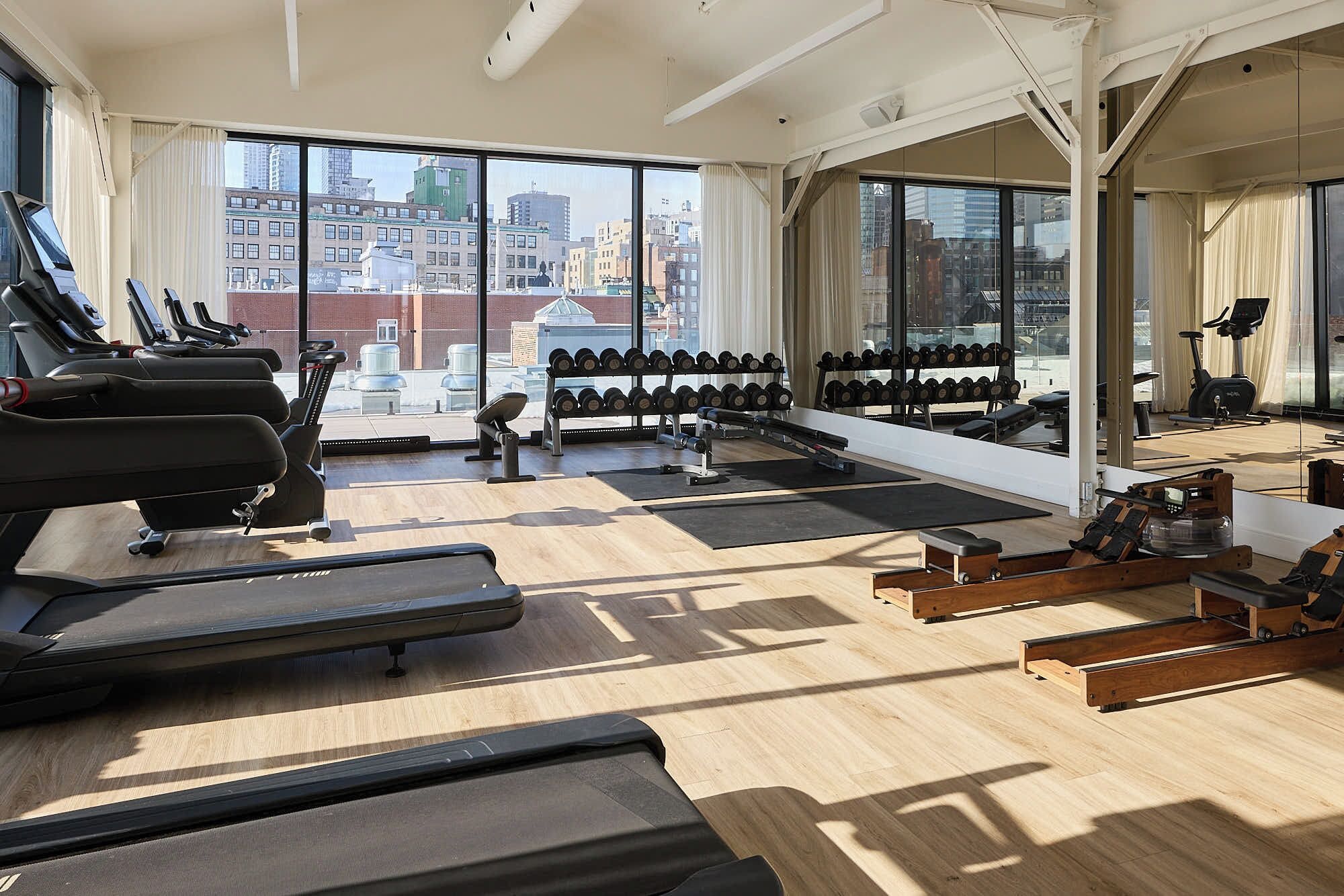 Ein Fitnessraum mit Laufbändern, Kurzhanteln und Trainingsgeräten.