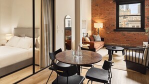 Una habitación de hotel con una cama, una mesa de comedor con sillas, un sofá y una pared de ladrillo.