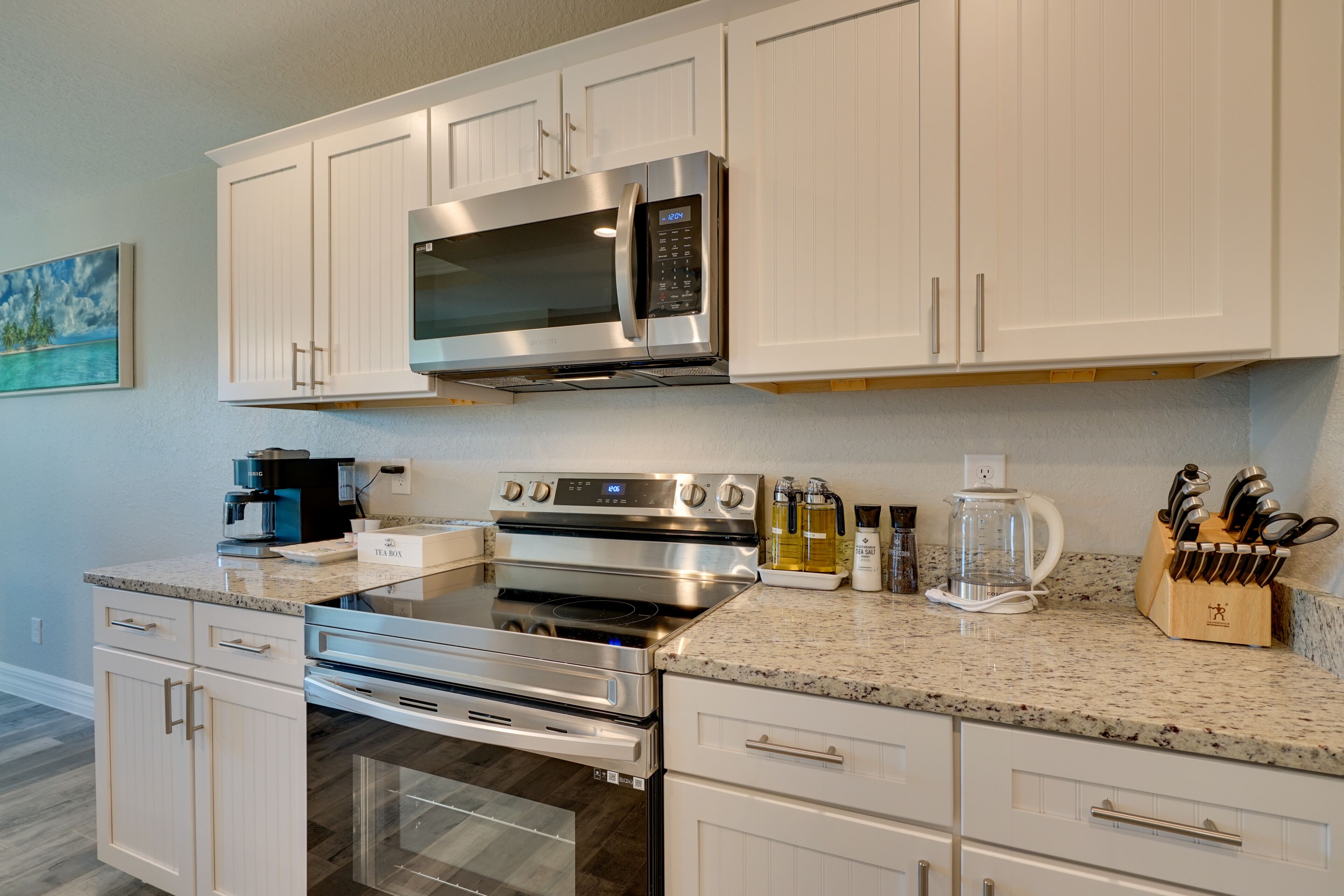 A modern kitchen with white cabinetry, stainless steel appliances, and granite countertops.