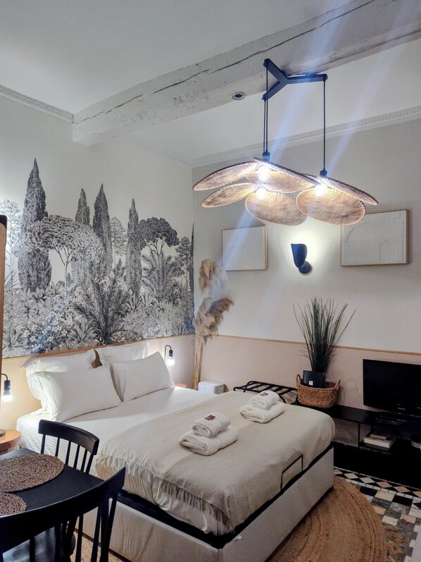 Un dormitorio moderno con una cama grande, un televisor montado en la pared y una lámpara en el techo.