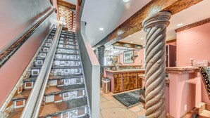 Una scala con piastrelle decorate, un pilastro in legno e un angolo cottura con mobili in legno e un bancone.