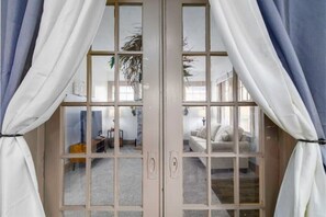 Una habitación con un ventanal grande, un sofá blanco y una pequeña mesa.
