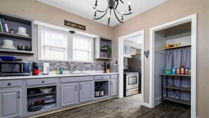 A kitchen with grey cabinets, a microwave, a stove, and a sign that says "Welcome to Country." - The Cedar House (Steubenville)