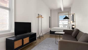 A modern room with a TV, sofa, and a bed.