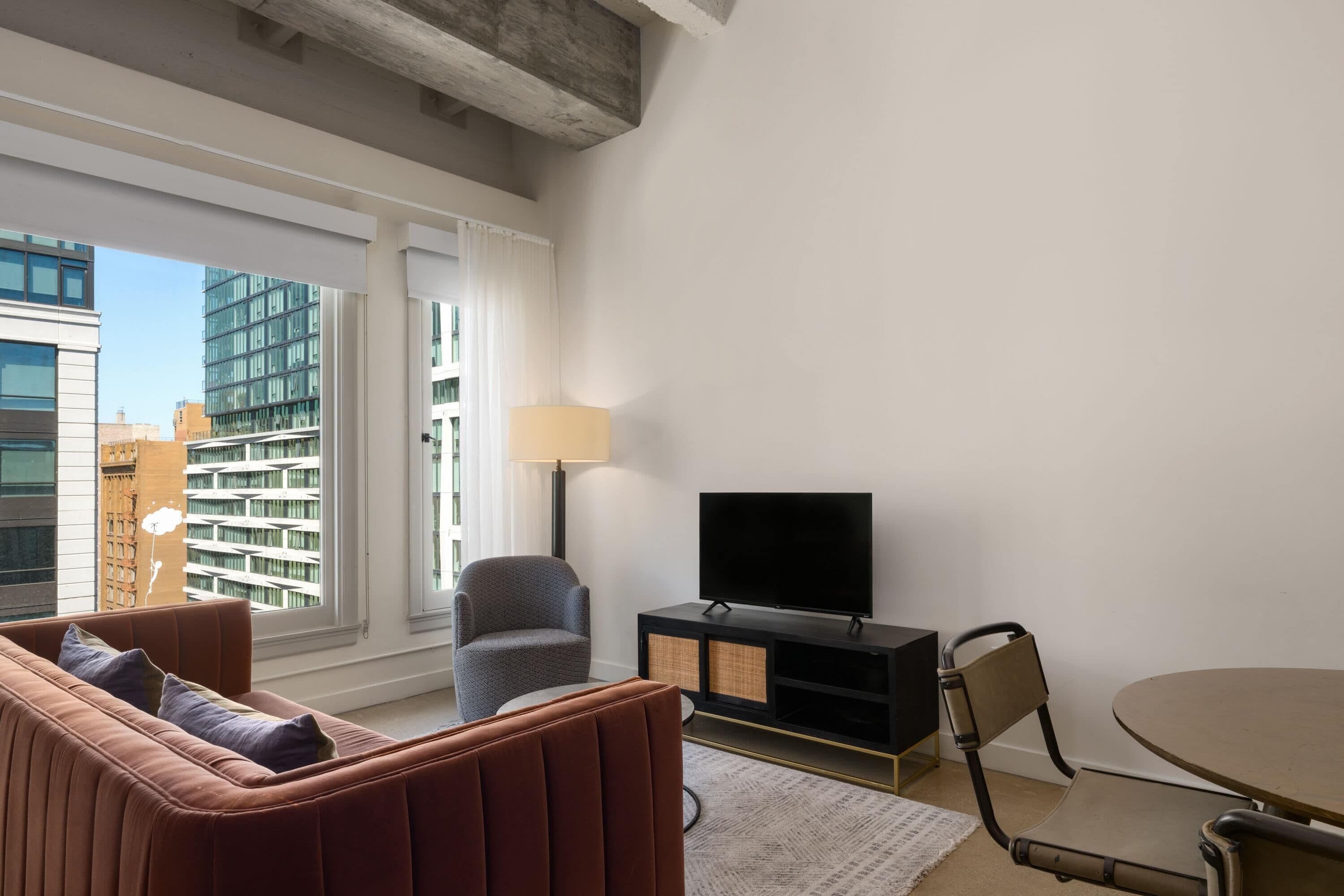 Ein modernes Wohnzimmer mit Sofa, Sessel, Fernseher und Esstisch.