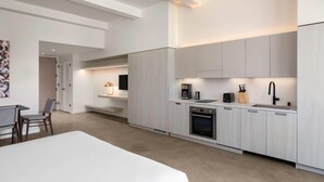 A modern kitchen with built-in appliances, a dining area with a table and chairs, and a hallway leading to a bedroom. - Reside Craftsman Los Angeles, a Wyndham Residence (Los Angeles)