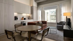 Une chambre d’hôtel moderne dotée d’un coin cuisine, d’une table à manger avec des chaises, d’un canapé, d’une petite table ronde et d’un téléviseur.