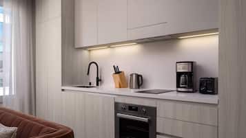 A modern kitchen with a built-in dishwasher, a coffee maker, and a kettle on the countertop.