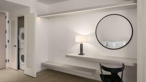 A modern bathroom with a built-in washing machine, a mirror, a lamp, and a chair. - Reside Craftsman Los Angeles, a Wyndham Residence (Los Angeles)
