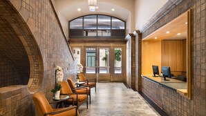A reception area with a check-in counter, seating, and a view through the glass doors. - Reside Craftsman Los Angeles, a Wyndham Residence (Los Angeles)