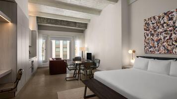 Une chambre d’hôtel avec un lit, un bureau, une chaise et un grand tableau abstrait accroché au mur.
