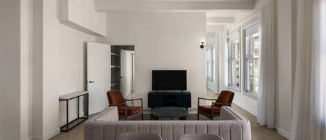 Una sala de estar moderna con un conjunto de sofá, una mesa de centro y un televisor de pantalla plana.