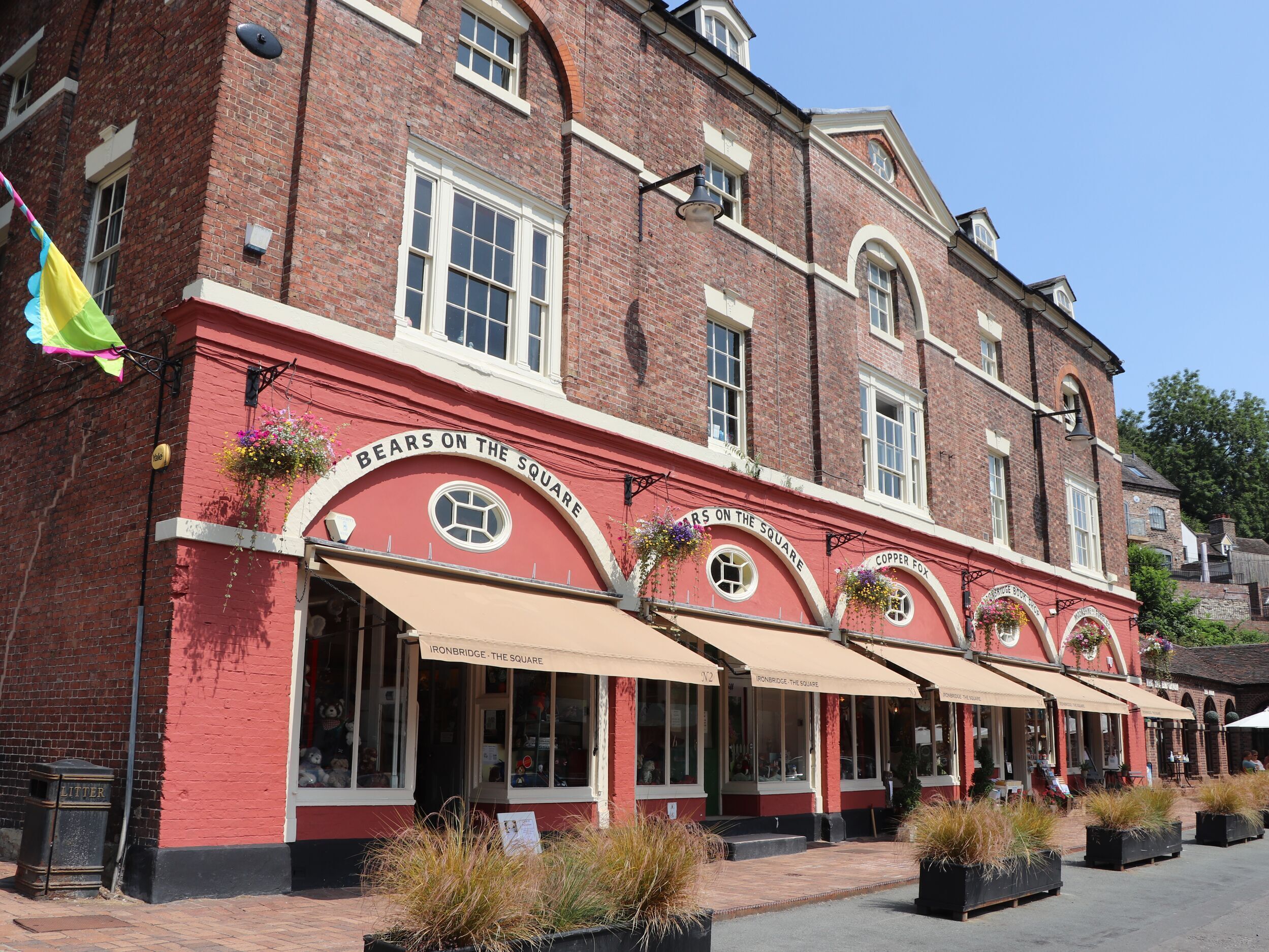 A red brick building with multiple storefronts, each with a sign reading "Ironbridge - The Square."