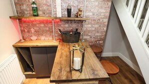 A compact kitchen with a rustic wooden counter, a brick wall, and a window with white railings. - The Olde Drill House (Telford)