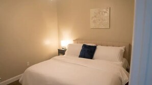 A hotel room with a large bed, a nightstand, a lamp, and a wall-mounted artwork. - Unit D (Moss Point)