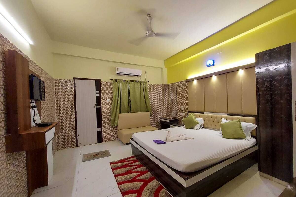 Una habitación de hotel con cama, escritorio, televisor y aire acondicionado.