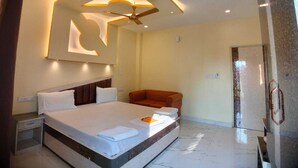 Une chambre d’hôtel moderne dotée d’un grand lit, d’un ventilateur de plafond et d’un coin salon.