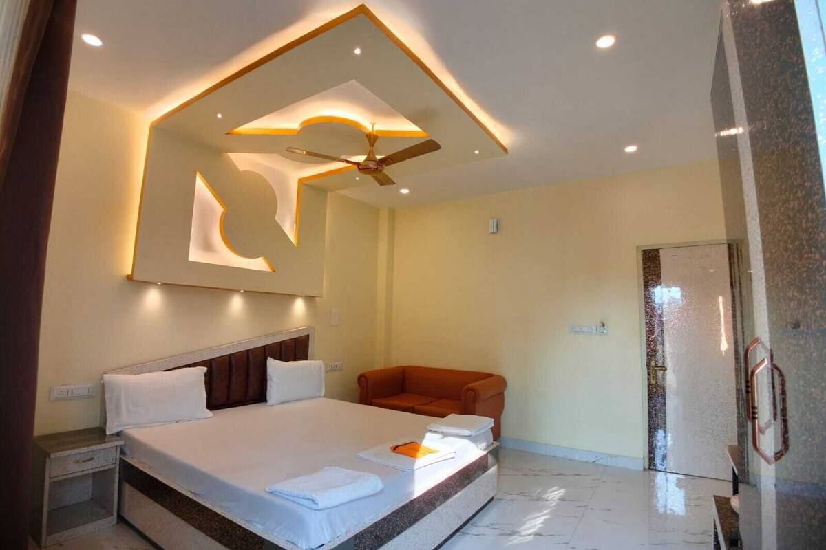 Una habitación de hotel moderna con una cama grande, un ventilador de techo y una zona de estar.
