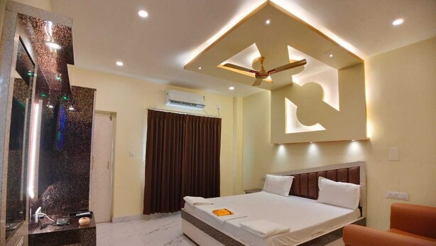 Une chambre d’hôtel moderne dotée d’un grand lit, d’un ventilateur de plafond, d’un téléviseur intégré et d’un sol en marbre.