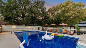 Ein Schwimmbecken mit einer Schwane als Schwimmgelegenheit, Liegestühlen und Sonnenschirmen.