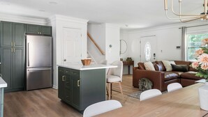 Eine moderne Küche mit dunklen Schränken, einem Edelstahlkühlschrank und einer weißen Kücheninsel.