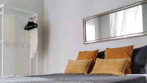 A bedroom with a bed, a mirror, and a wardrobe.