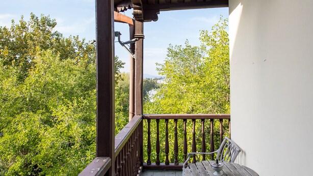A wooden balcony with a railing, a bench, and a table. - HB apartments Akhvelediani  (Tbilisi)