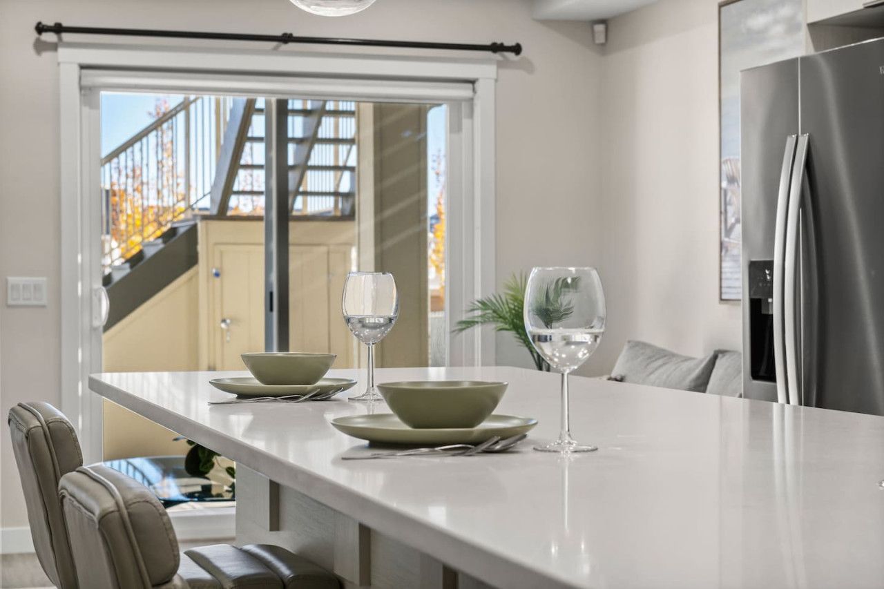 A modern kitchen with a white countertop, two green bowls, and two wine glasses.