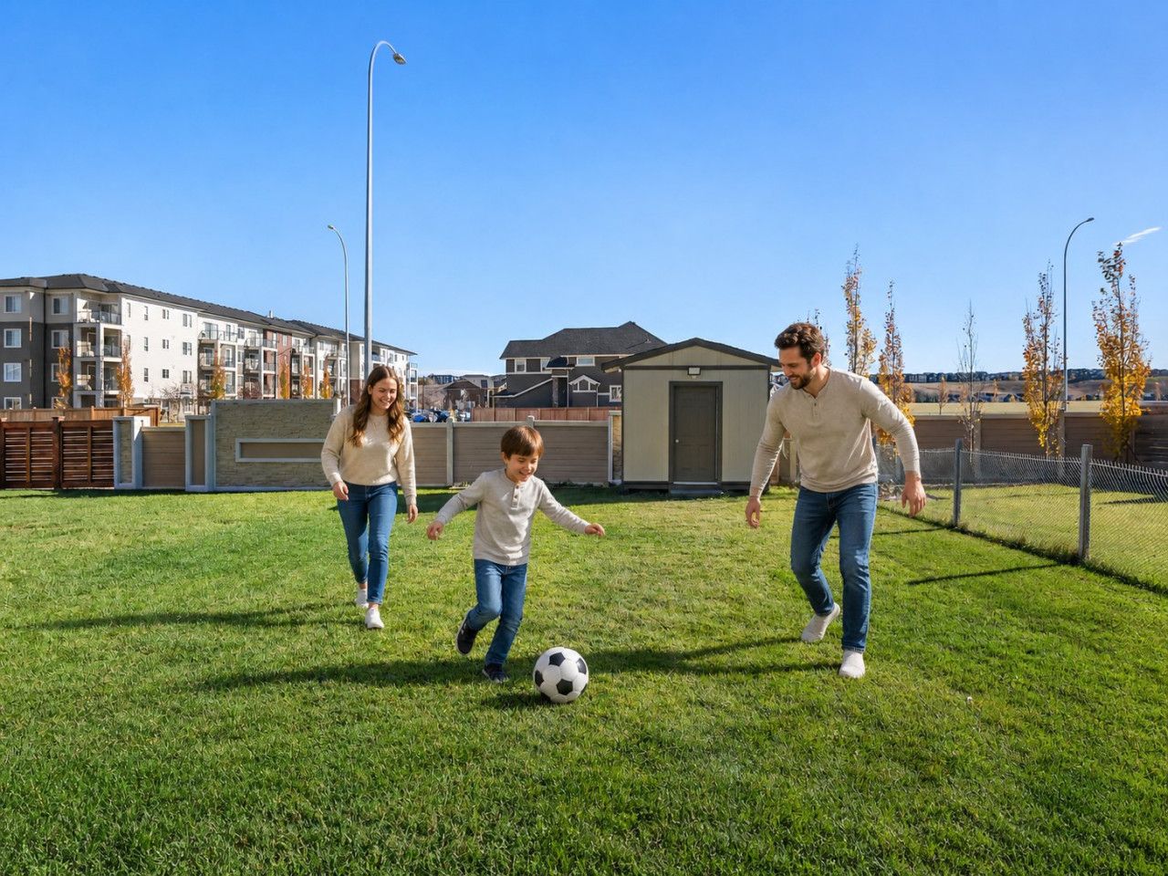 A family playing soccer on a grassy field with buildings in the background.