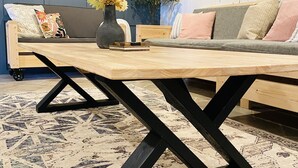 Een moderne woonkamer met een houten salontafel, een bank met kussens, een potplant en een spiegel aan de muur.