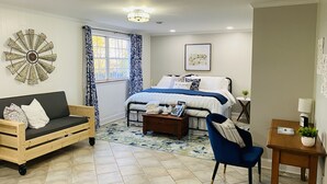 Een slaapkamer met een bed, een houten bank, een blauwe fauteuil, een bijzettafeltje en een decoratief wandobject.