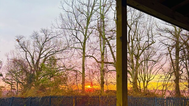 Een bubbelbad met uitzicht op een zonsondergang en bomen.