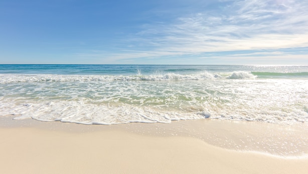 Ein Strand mit blauem Himmel und sanften Wellen.