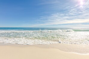 Una playa con cielos despejados y olas suaves.
