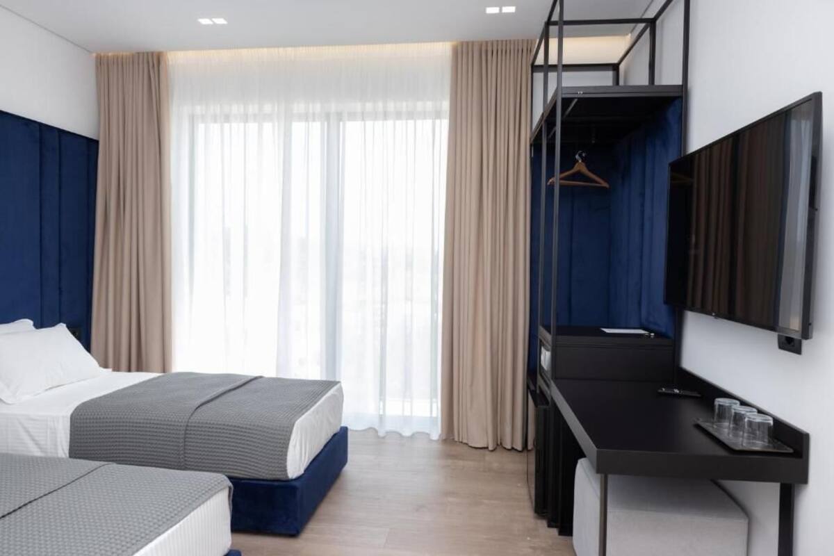 A modern hotel room with a bed, a desk, and a TV.