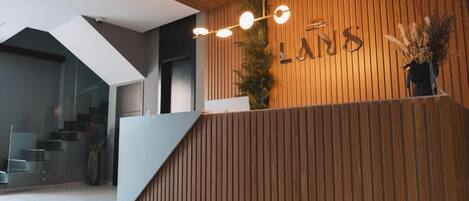 A modern reception area with a wooden reception desk, a staircase, and a glass wall.