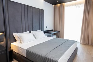 A modern hotel room with a large bed, a desk, and a view of the outdoors. - Lans Hotel (Ksamil)