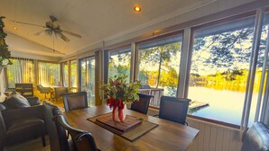 A dining area with a wooden table, chairs, and a view of a lake through large windows.